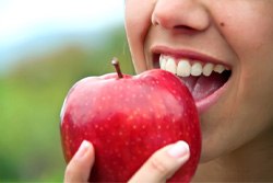 Closeup of patient with dental implants in Plano eating an apple 