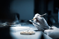 Gloved hands creating dental crowns at a workstation