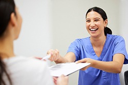 Medical staff handing forms on clipboard to patient