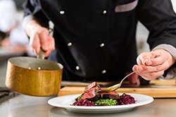 A chef pouring sauce over a steak.