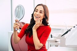 Woman in a red shirt checking smile in the mirror