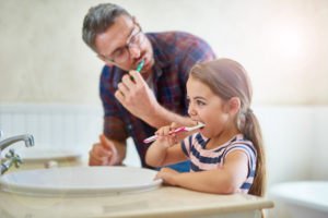 Father and daughter practicing healthy at-home dental habits during quarantine