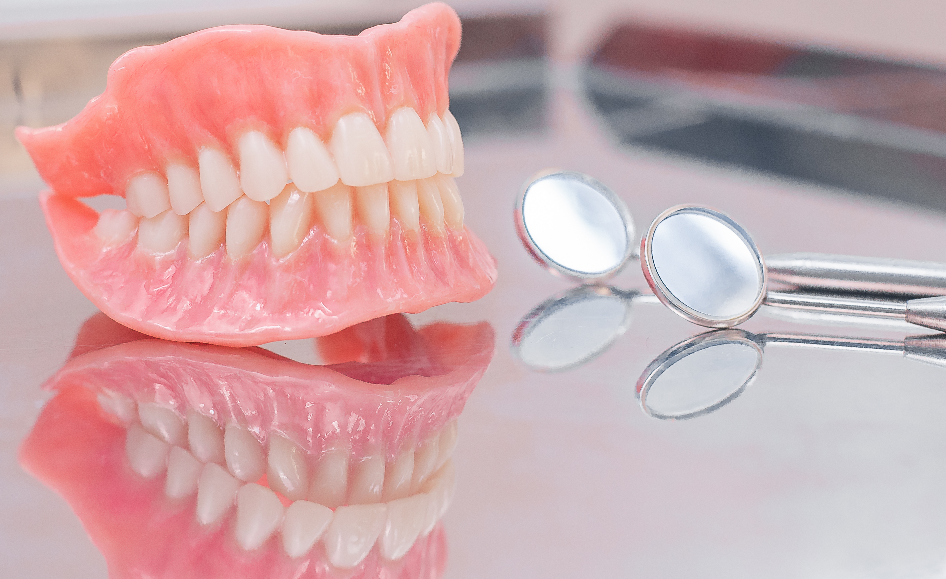 Denture on table next to dental mirror