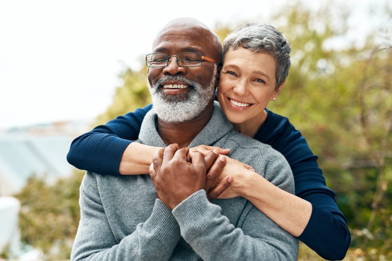 Older patient and partner smiling as they hug